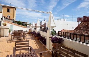 A rooftop terrace with wooden benches, potted plants, and a white railing. - Hostal América (Madrid)