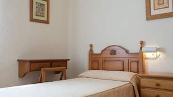 A bedroom with a wooden bed, a nightstand, a bedside table, and a wall-mounted light fixture.