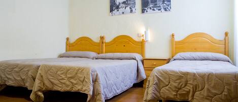 A hotel room with two single beds, wooden headboards, and a nightstand with a lamp.