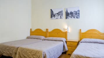 Ein Zimmer mit zwei Holzbetten, jeweils mit passendem Nachttisch und Wandlampe.