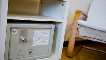 A metal safe with instructions in Spanish, a lock, and a wooden chair in the background.