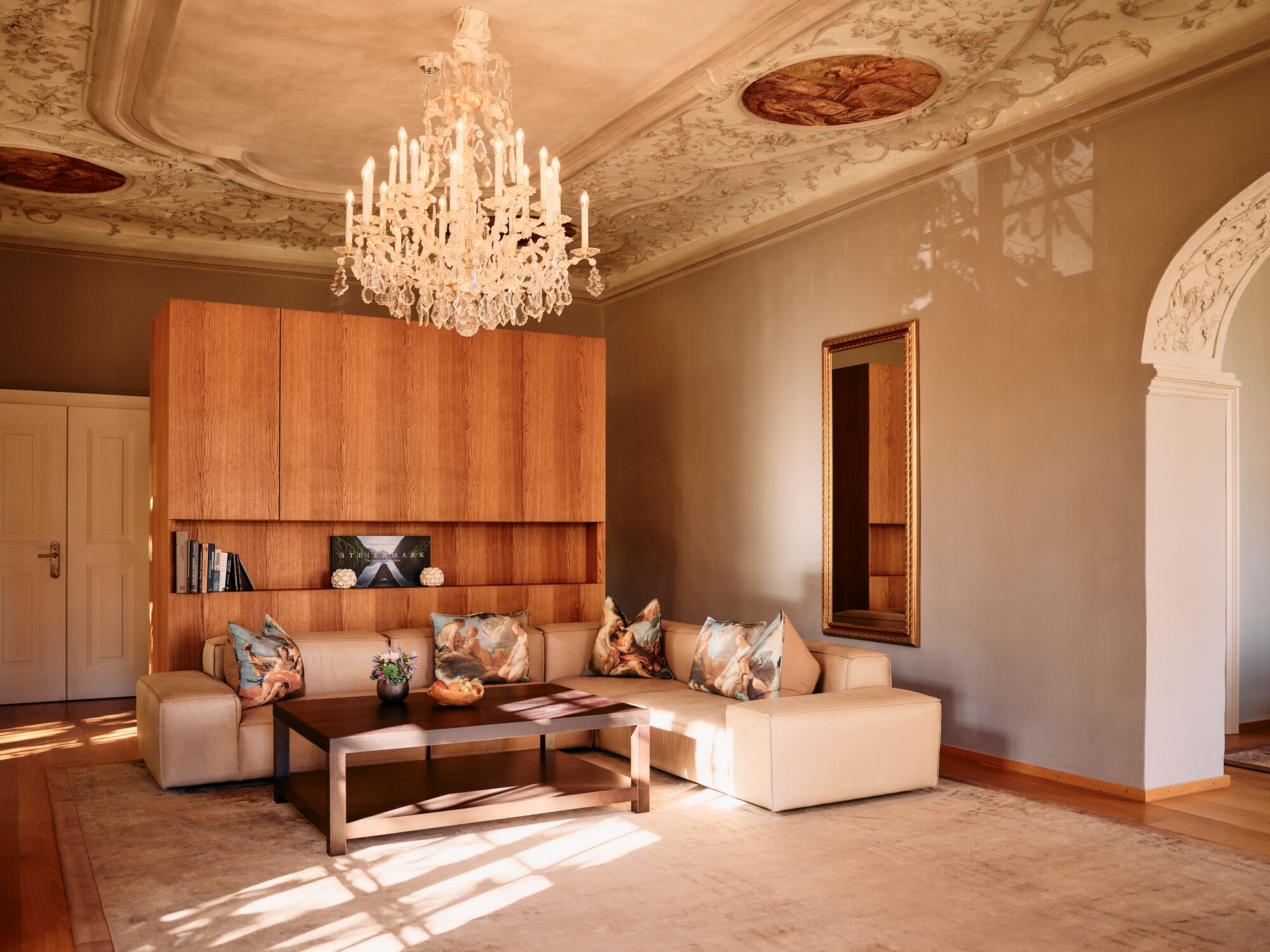 Un salon spacieux agrémenté d’un grand lustre, d’un mur d’accent en bois, d’un ensemble de canapés et d’une table basse.
