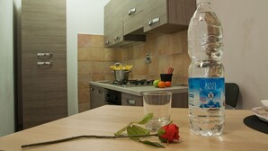 A kitchen with a wooden cabinet, a stove, and a table with a water bottle and a glass. - Maison Re di Roma (Rome)