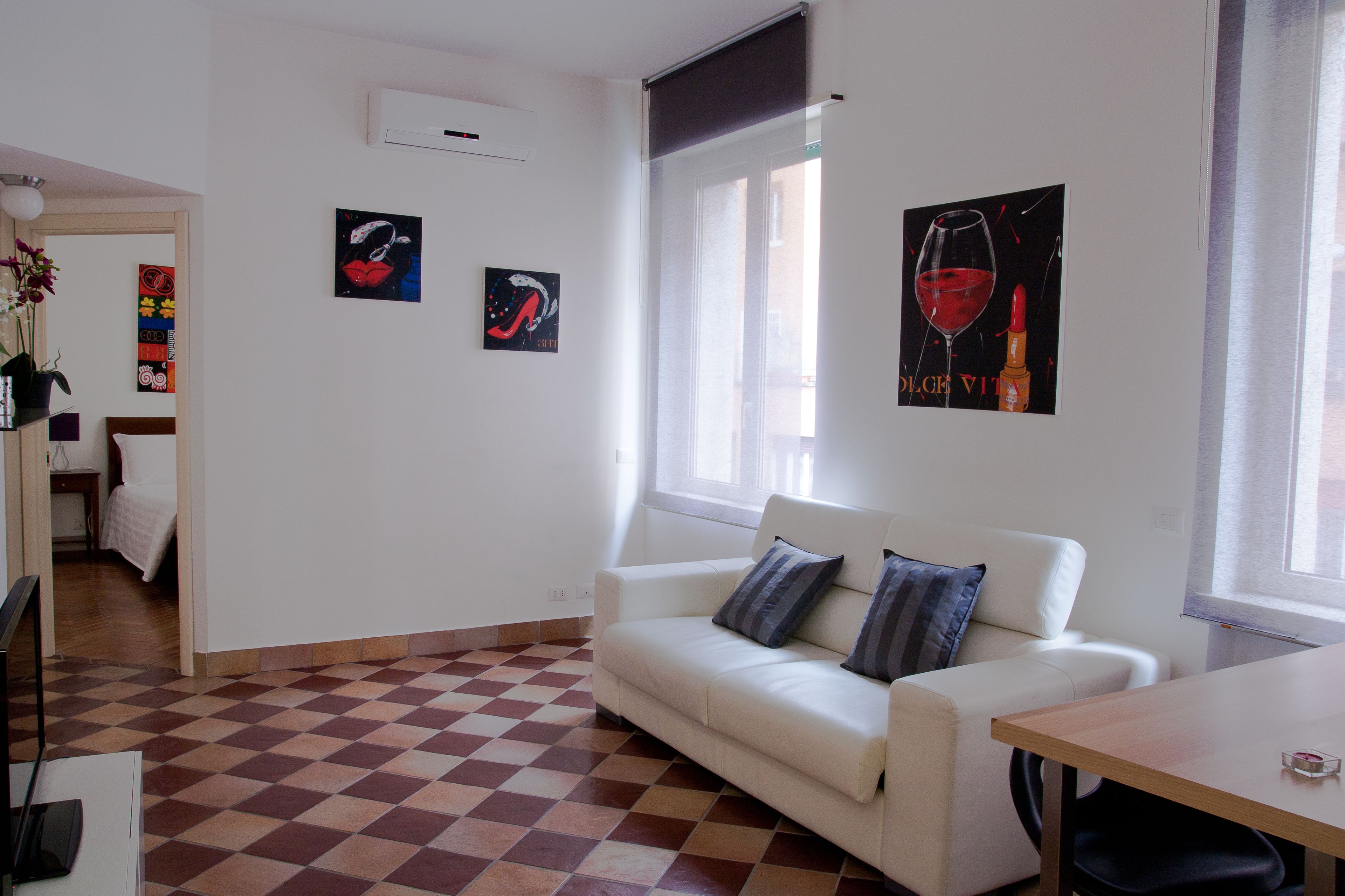 A modern living room with a white sofa, checkered floor, and artwork on the walls.