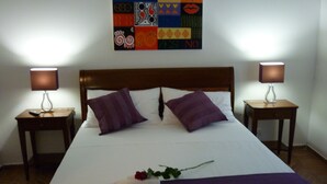 A neatly made bed with a purple blanket, two nightstands with lamps, and a colorful wall decoration. - Maison Re di Roma (Rome)