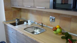 A kitchen with a stainless steel sink, a kettle, and a fruit bowl containing apples and lemons. - Maison Re di Roma (Rome)