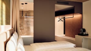 A modern hotel room with a bed, a hanging shower, and a coffee machine on a side table. - TAUROA Schönberghof Spielberg (Spielberg)
