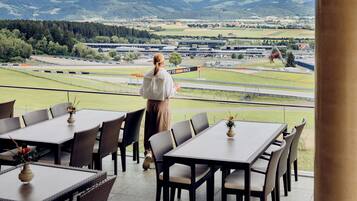 A person standing at a table with a view of a race track and surrounding landscape.
