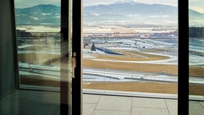 A view from a room with large windows overlooking a snowy landscape with mountains and a complex of buildings. - TAUROA Schönberghof Spielberg (Spielberg)