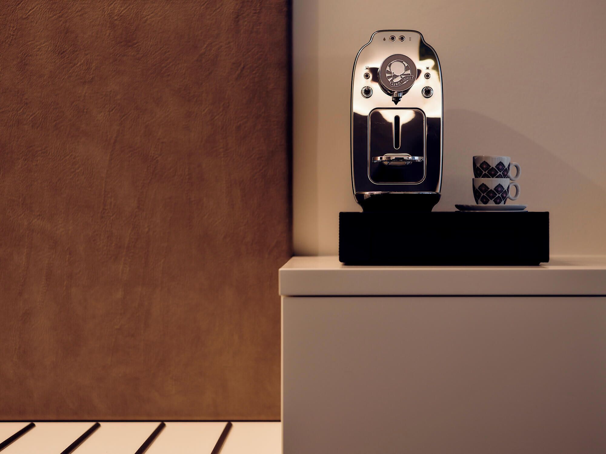 A coffee machine with a control panel and a cup and saucer on a black stand.