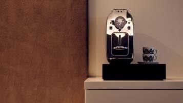 A coffee machine with a control panel and a cup and saucer on a black stand.