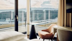 A modern hotel room with a large window offering a view of a snowy landscape and mountains. - TAUROA Schönberghof Spielberg (Spielberg)