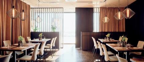 Un restaurante moderno con una amplia zona de comedor, mesas y sillas de madera.