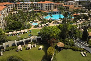 A resort with multiple swimming pools, sun loungers, and palm trees.