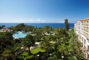 Et resort med swimmingpool, frodigt grønt område og havudsigt.