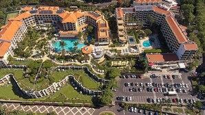 Un complejo turístico con varias edificaciones, una piscina central y un estacionamiento.