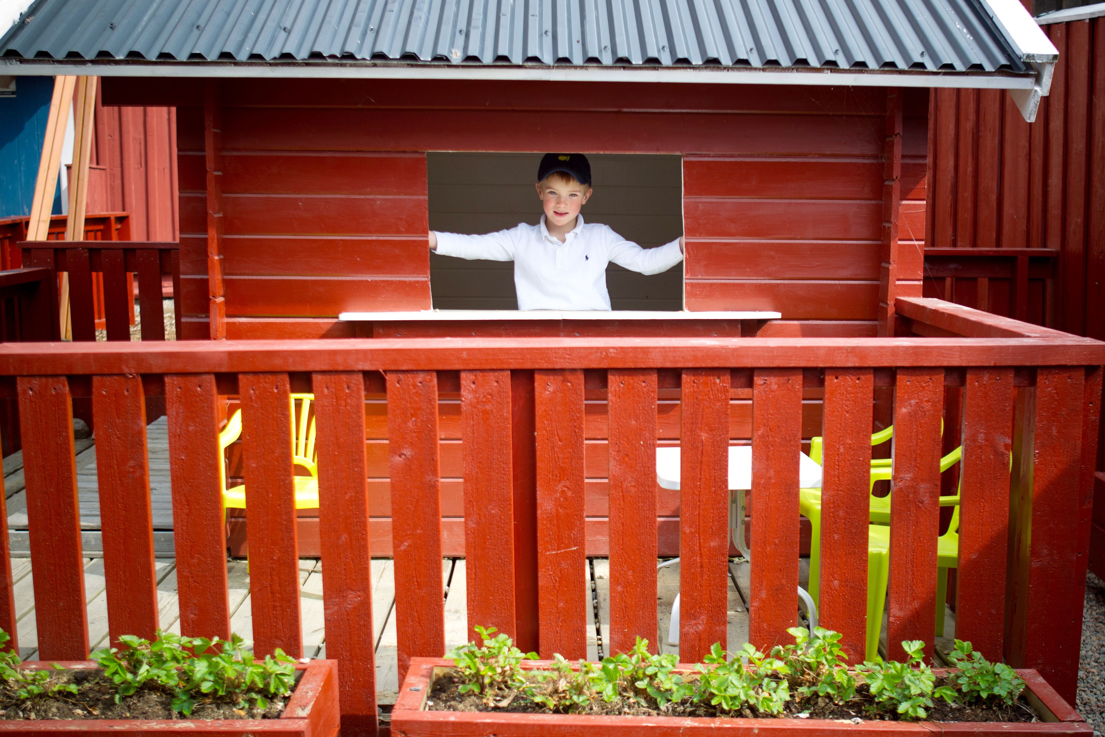 A red wooden structure with a window and a bench.