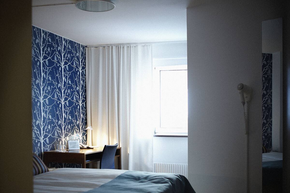 Ein Hotelzimmer mit Bett, Schreibtisch, Stuhl und Fenster.