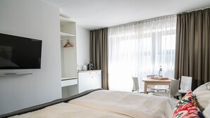 A hotel room with a bed, a desk, a chair, a television, and a window with curtains. - BIG MAMA Berlin (Berlin)