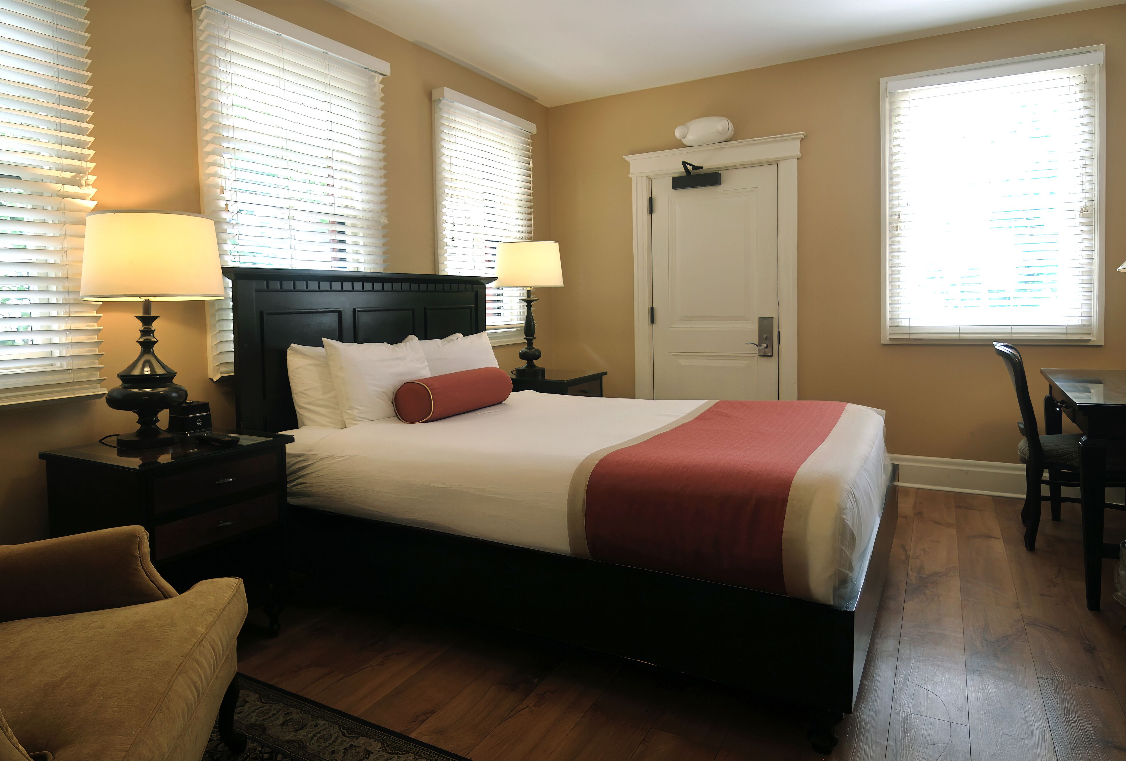 Une chambre à coucher bien aménagée, avec un grand lit, deux tables de chevet avec des lampes, une chaise et un bureau.