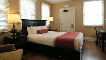 A neatly arranged bedroom with a large bed, two bedside tables with lamps, a chair, and a desk.