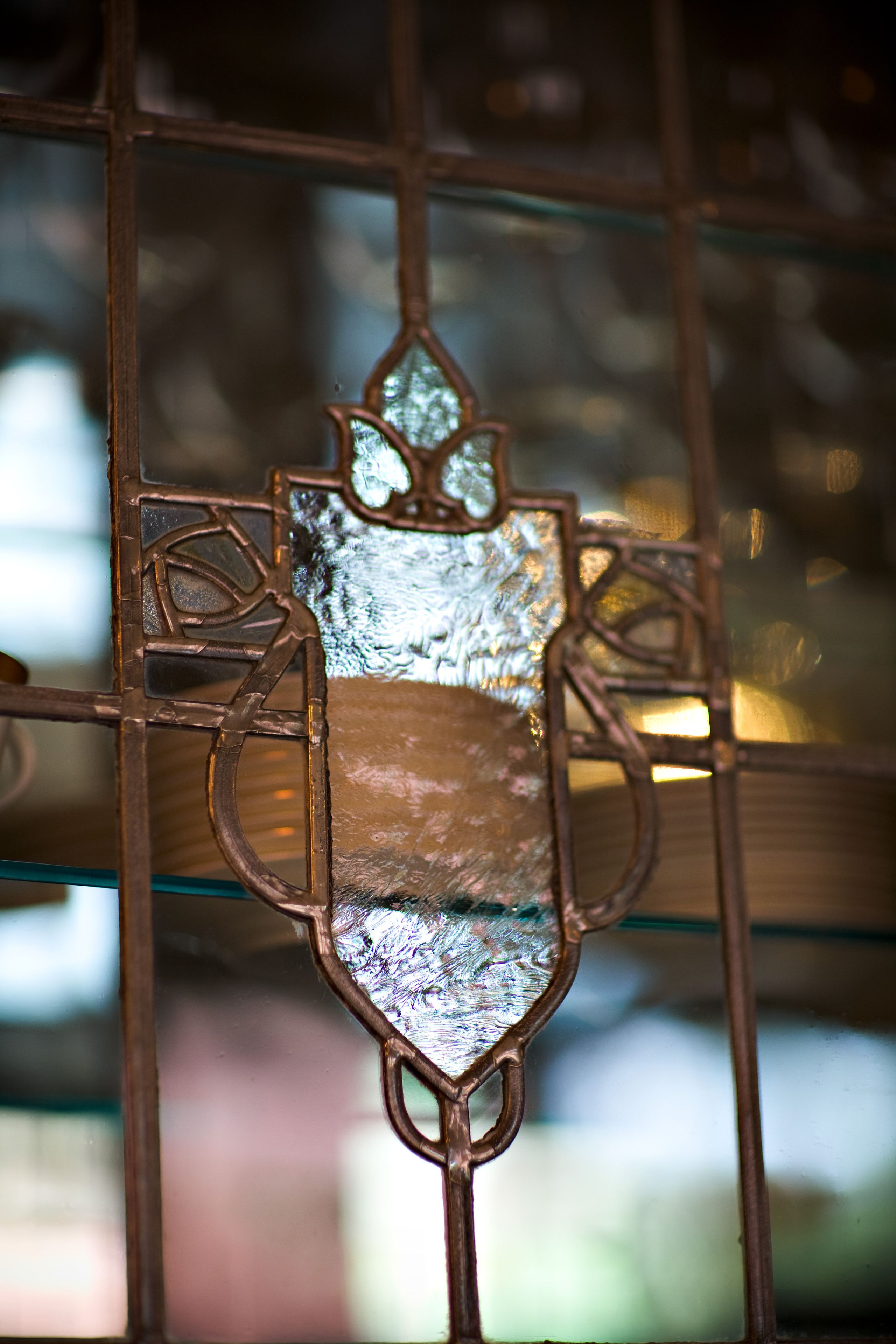 A stained glass window with a geometric design, set within a metal frame.