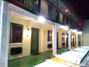 A corridor with multiple rooms, each with a door and a window. The corridor has a green floor and white walls.