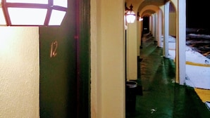 A corridor with a door marked '12', a lit lantern, and a snow-covered exterior. - Granada Inn Motel (Kalkaska)