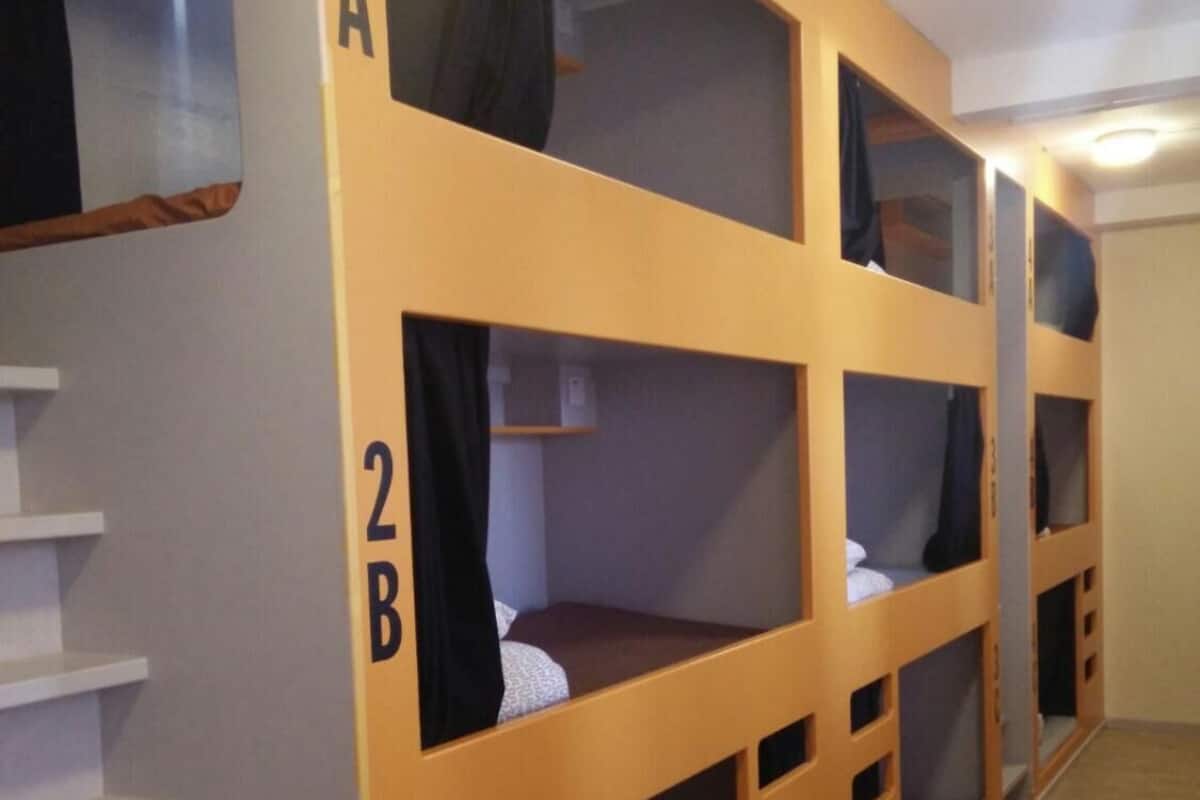 A room with bunk beds labeled 2A, 2B, and 2C, wooden flooring, and a staircase.
