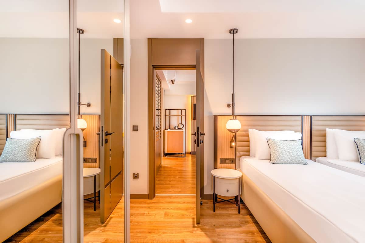 A hotel room with two beds, a small round table, and a mirror.