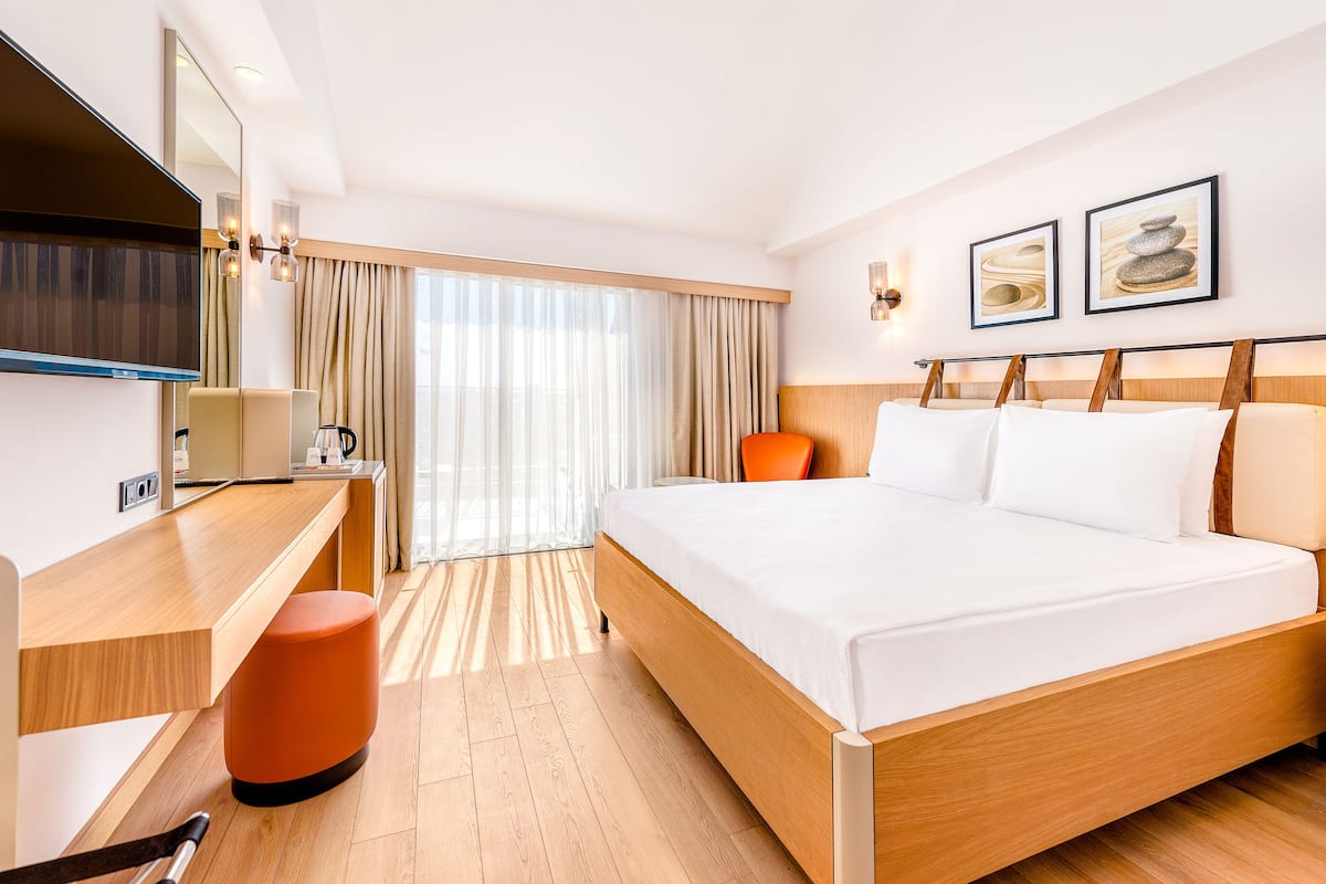A modern hotel room with a wooden bed, a desk, and a television.
