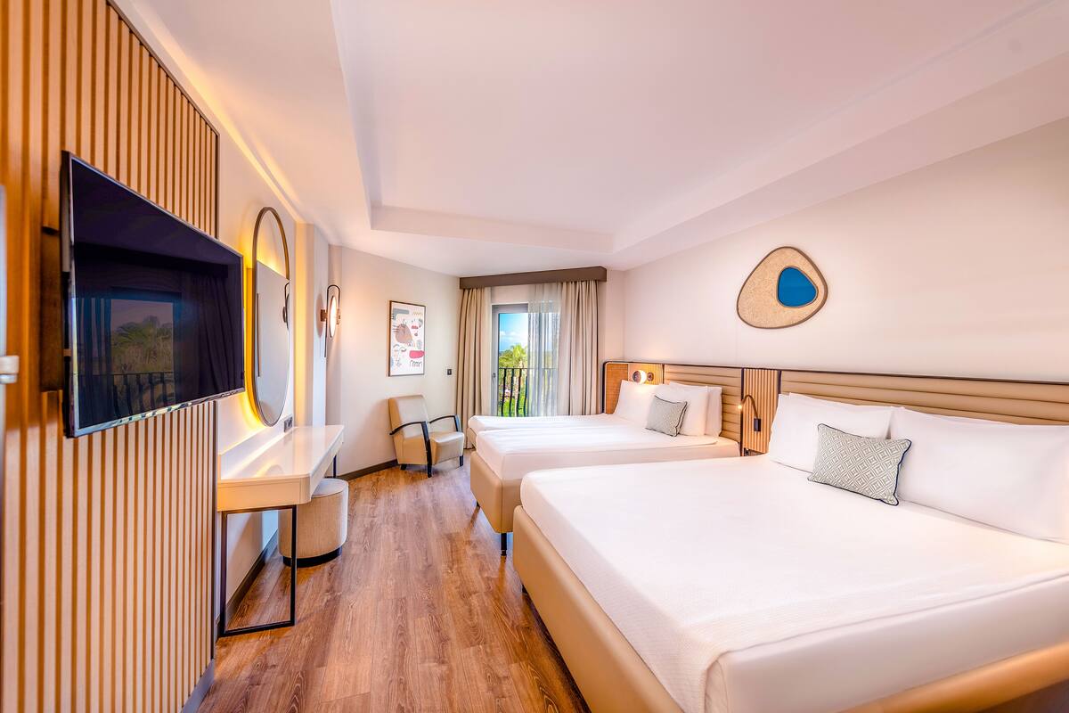 A hotel room with two beds, a TV, a desk, and a chair.