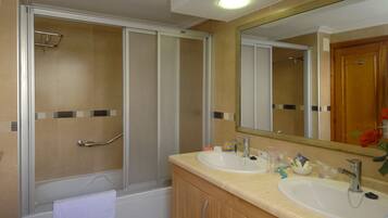 Une salle de bain avec deux lavabos, une douche et un grand miroir.