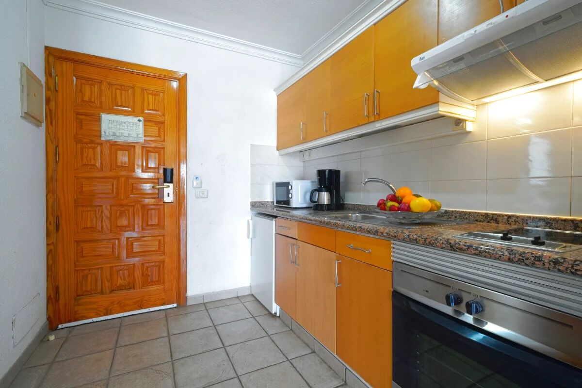 A kitchen with wooden cabinets, a stainless steel stove, and a countertop with a coffee maker and fruit.