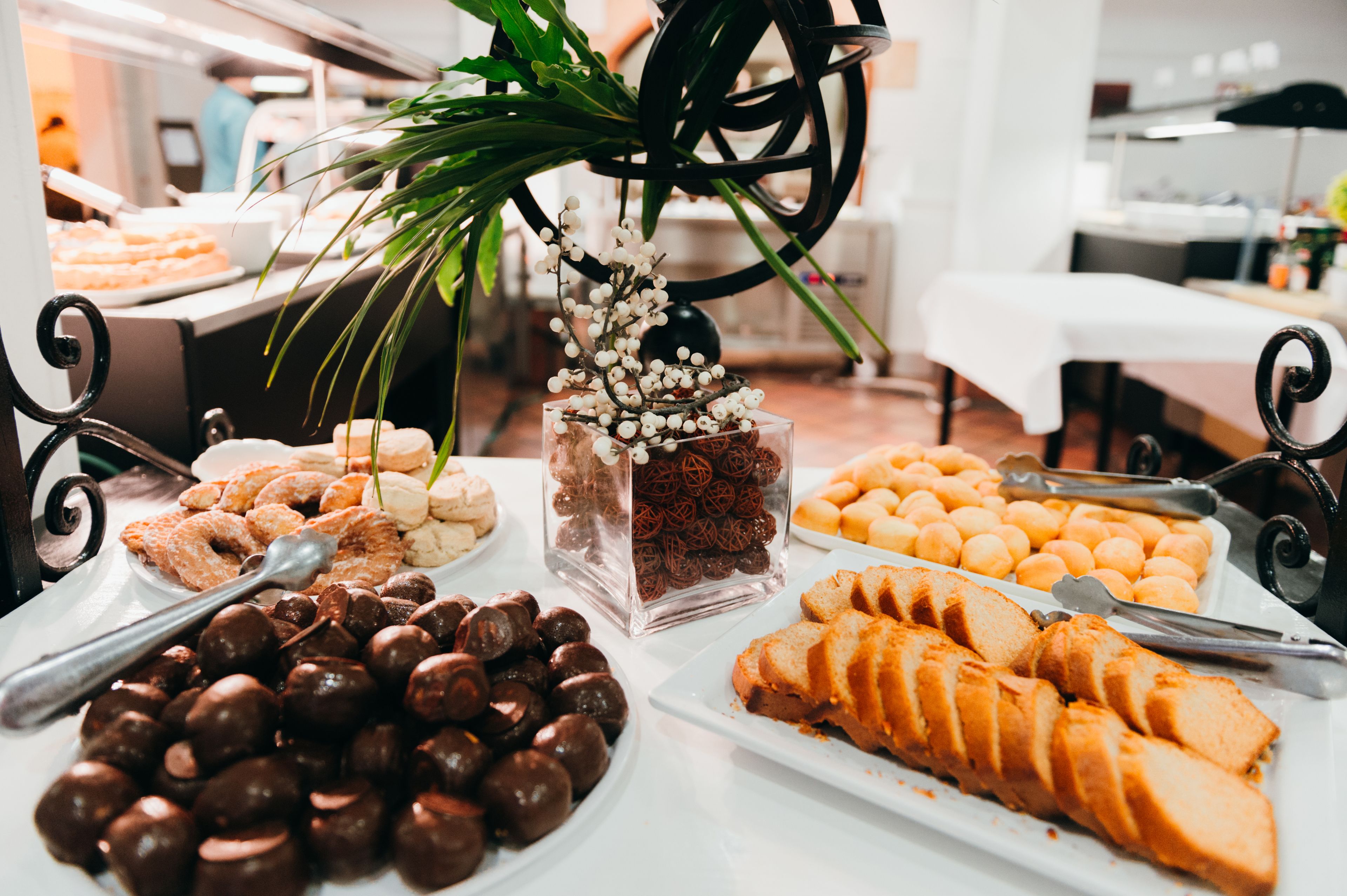 Una mesa de buffet con diversas opciones de comida, incluyendo bolitas de chocolate, pasteles y pan en rebanadas.