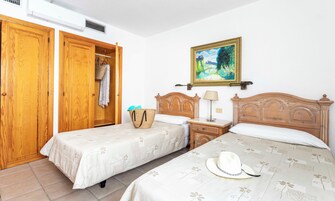 Ein Schlafzimmer mit zwei Betten, Holzschränken, einem Gemälde und einem Nachttisch mit Lampe.
