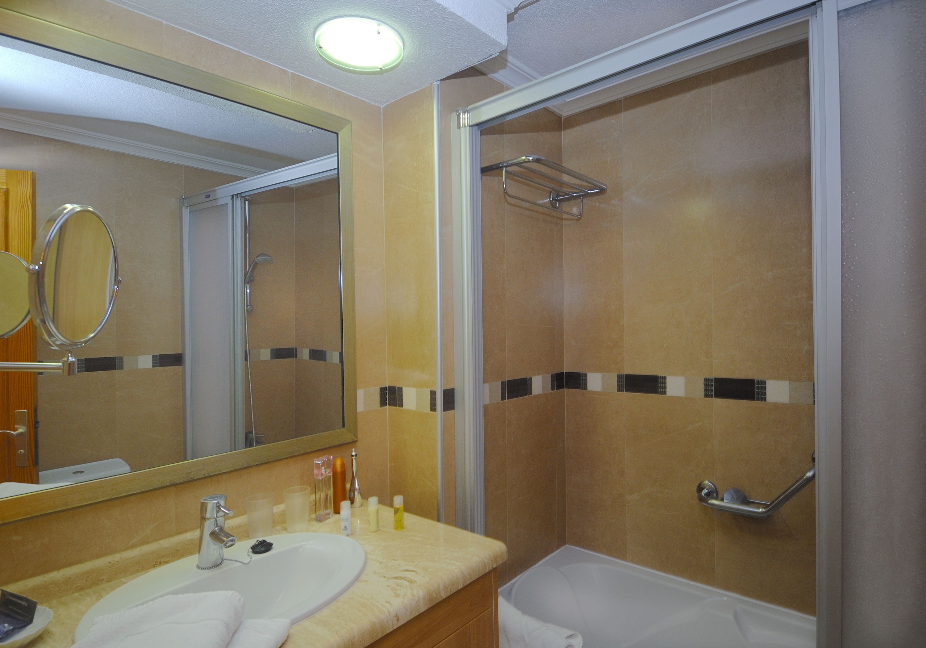 A bathroom with a sink, mirror, and shower.