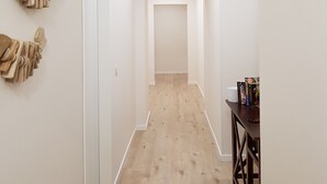 A hallway with a clock, wooden flooring, and a wall-mounted sculpture. - B&B Gisira (Catania)