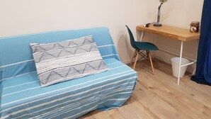 A room with a blue-striped sofa, a wooden desk, a teal chair, and a small trash bin. - B&B Gisira (Catania)