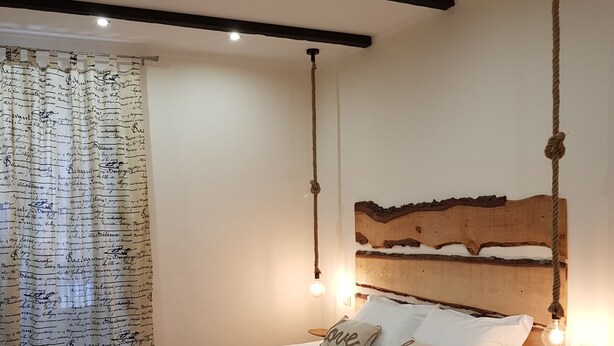 A bedroom with a bed, headboard, bedside tables, and a curtain with handwritten text. - B&B Gisira (Catania)