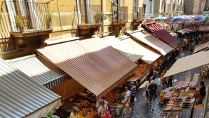 An outdoor market with various stalls selling fruits, vegetables, and other goods. - B&B Gisira (Catania)