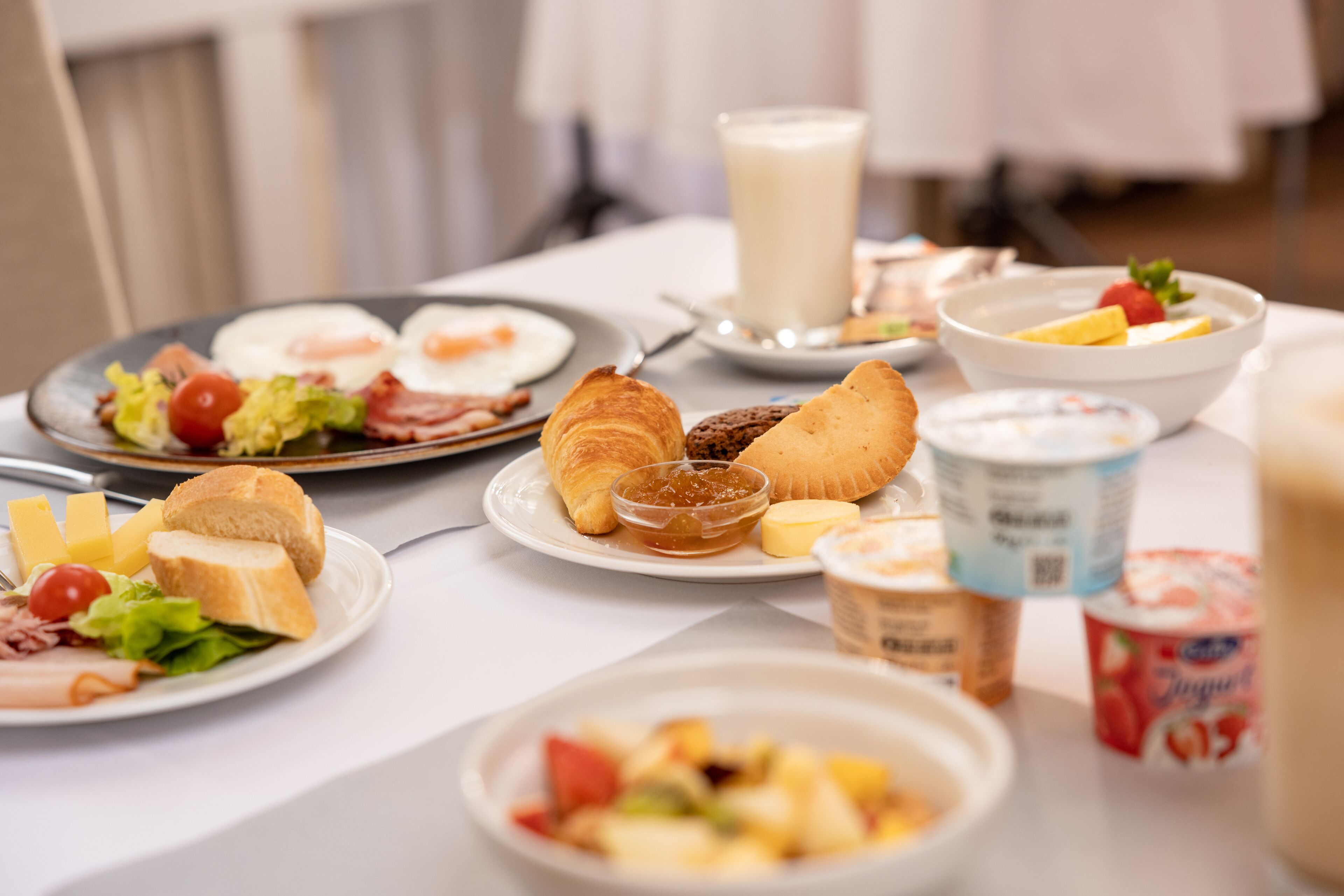 Ein reichhaltiges Frühstücksbuffet mit verschiedenen Speisen, darunter Eier, Croissants und Obst.