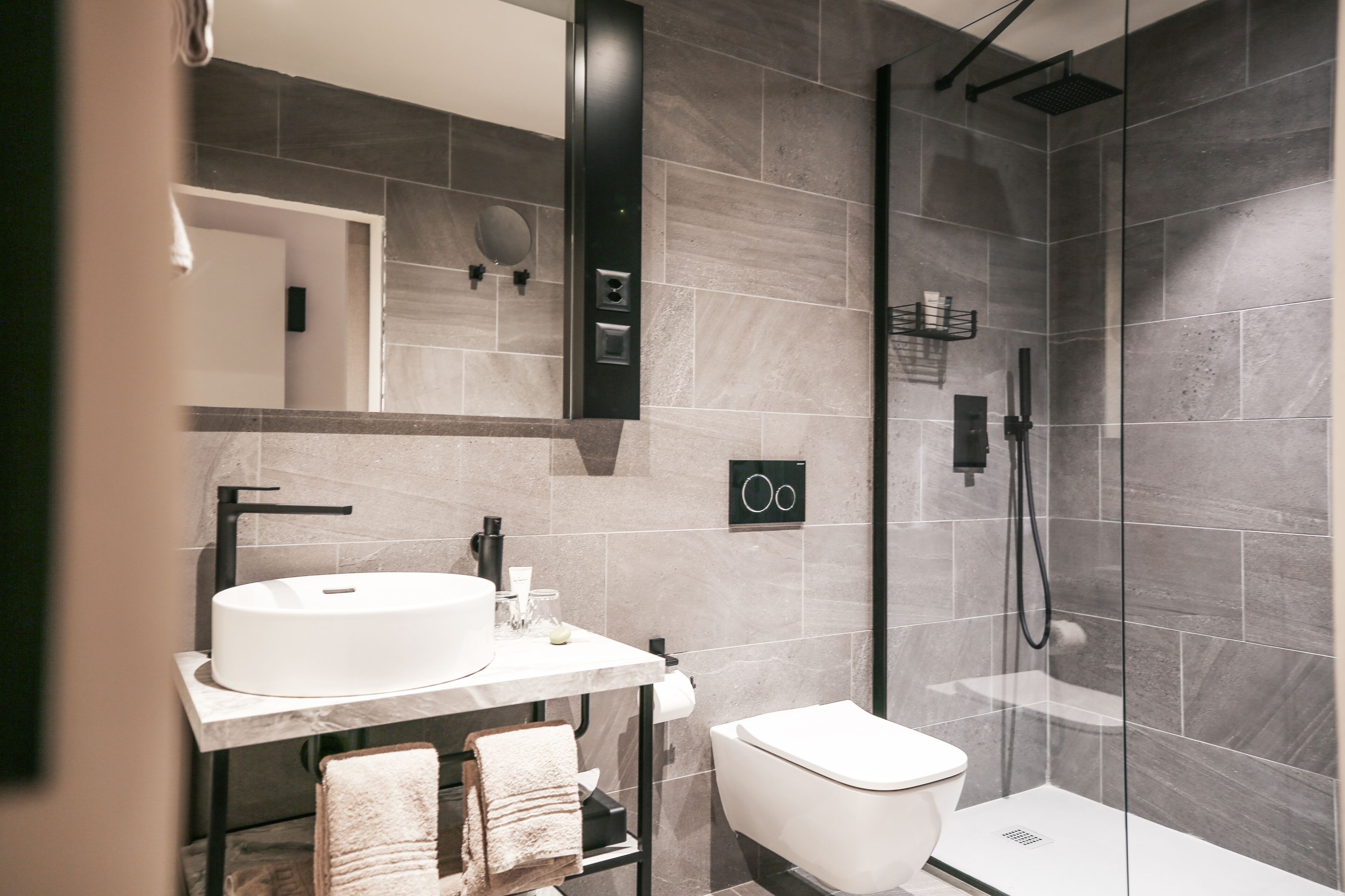 Un baño moderno con lavamanos blanco, inodoro y ducha con mampara de vidrio.