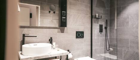 A modern bathroom with a white sink, toilet, and glass-enclosed shower.