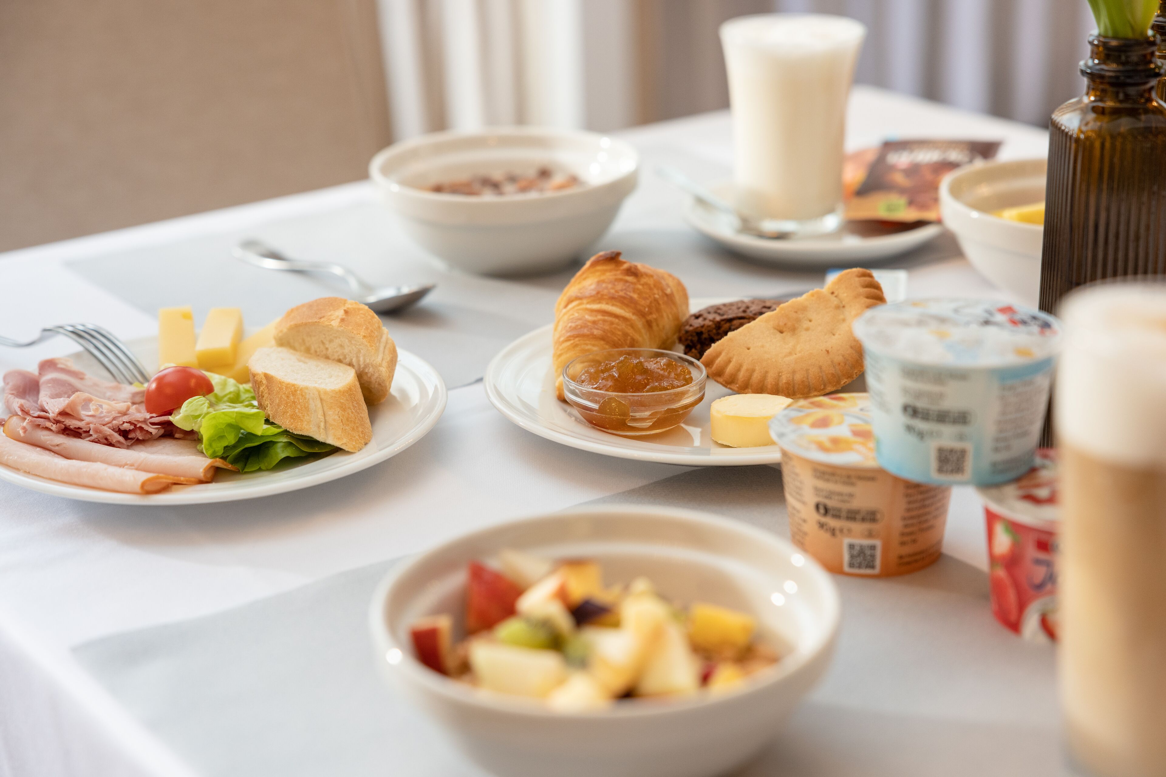 A breakfast buffet with various food items including bread, pastries, fruits, and dairy products.