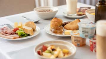 A breakfast buffet with various food items including bread, pastries, fruits, and dairy products.