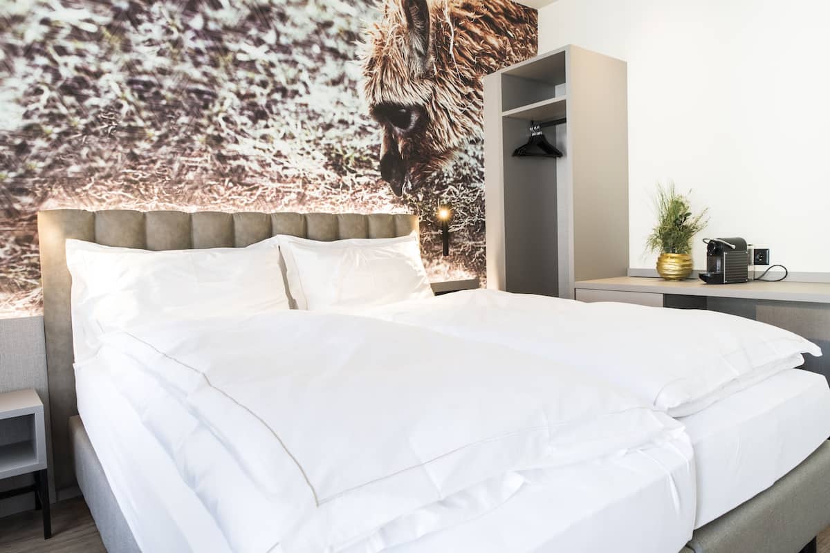 A neatly made bed with white linens, a tufted headboard, and a wall mural of a horse.
