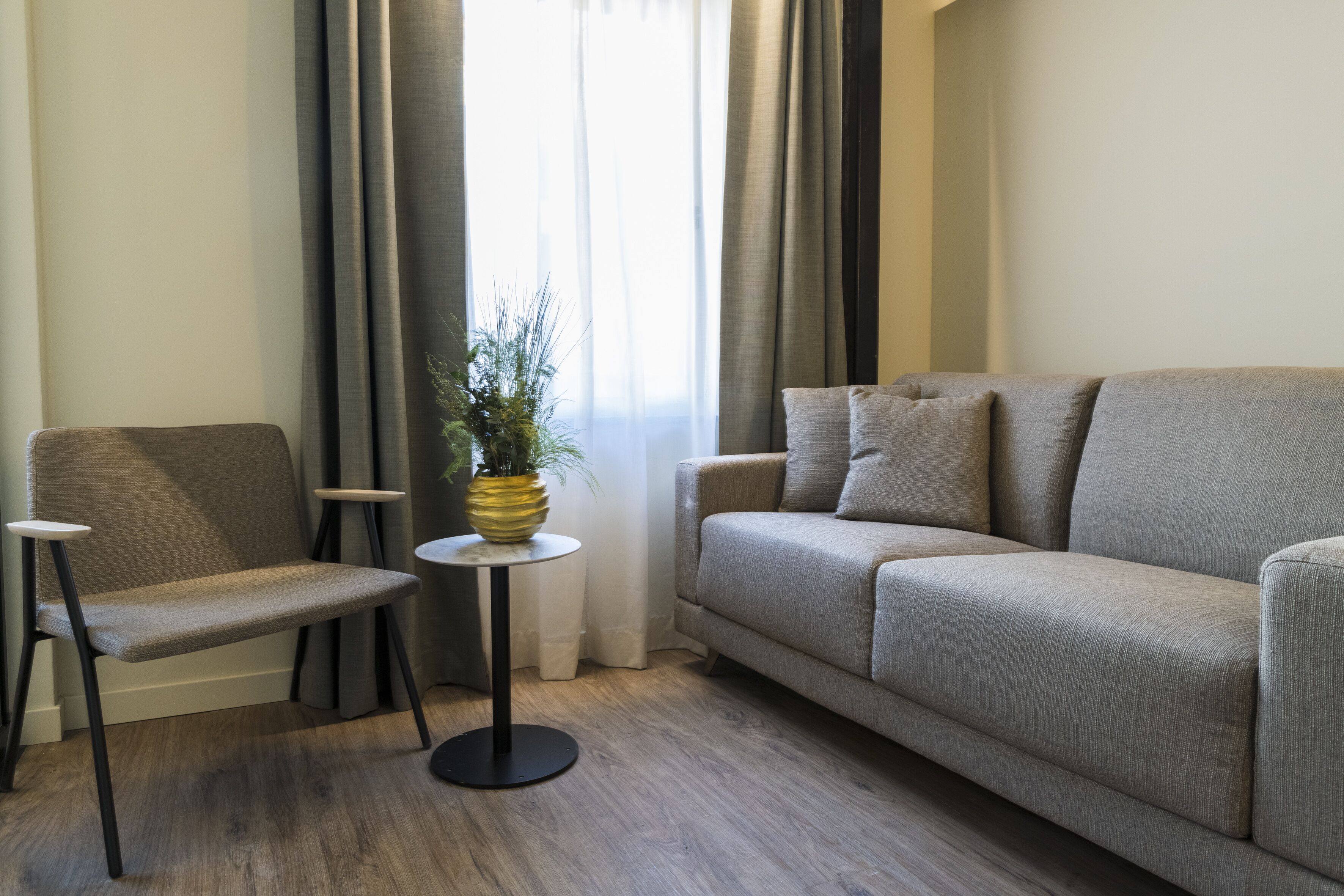 Una sala de estar con un sofá, un sillón, una mesita y una planta en maceta.