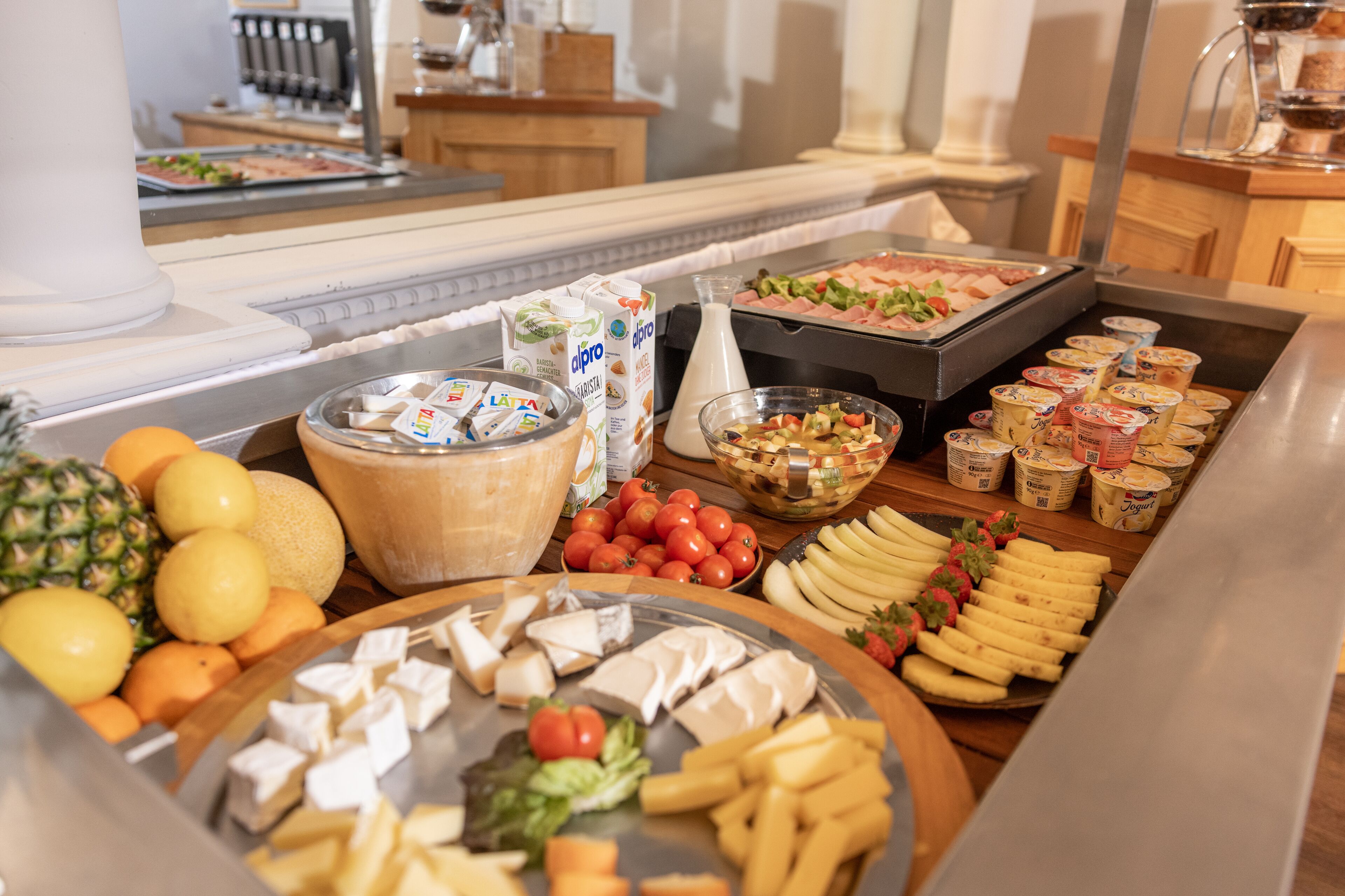 A buffet with various food items including fruits, cheeses, and yogurt.