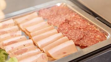A buffet with sliced meats and vegetables.
